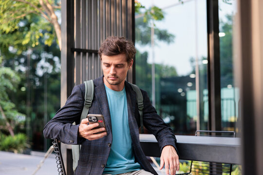 A man in a blazer checking his smartphone outdoors