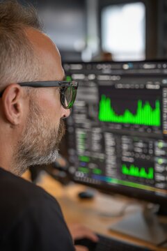 It security specialist studying real time green analytics on multiple monitors for website banner and corporate background design