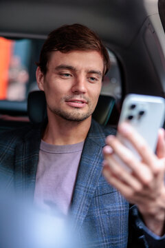 Man checking his smartphone while riding in a car
