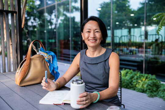 Professional woman smiles while sitting with her notebook outdoors.