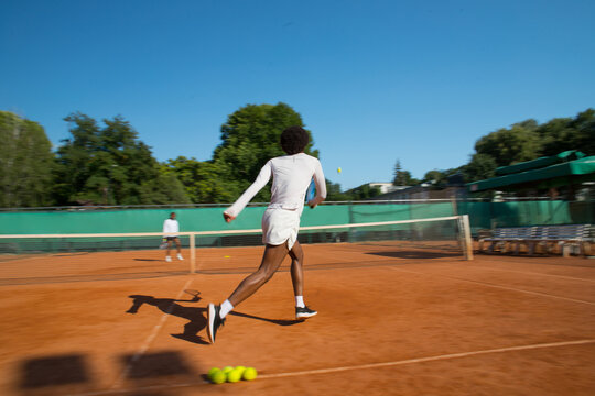 Black man tennis player blurred into motion with racket and ball.