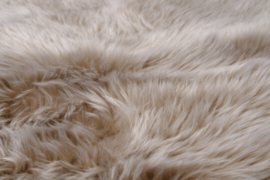 Perspective close-up of soft beige faux fur carpet texture for interior background