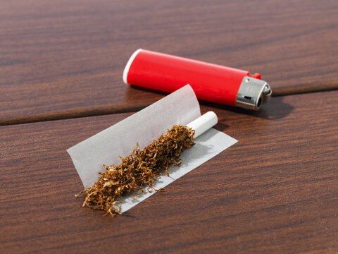 Hand-Rolling Cigarette Setup with Loose Tobacco and Red Lighter