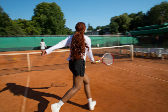 Black woman tennis player blurred into motion with racket on court.