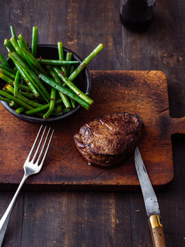 A beef steak is served on a wooden board 