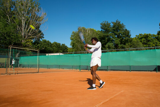 Black man tennis player blurred into motion with racket and ball.