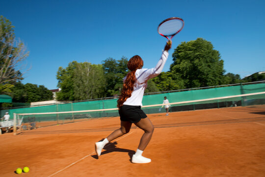 Black woman tennis player blurred into motion with racket on court.