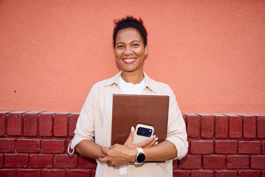 Portrait of a businesswoman smiles in front of the wall