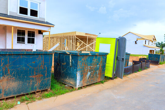 Construction takes place with waste containers portable restroom beside building site