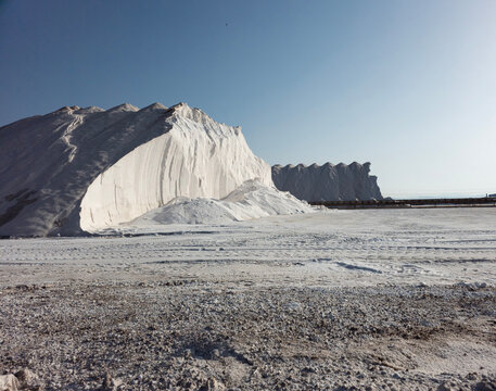 Massive salt pyramids at a salt production factory under a clear blue sky during daylight hours