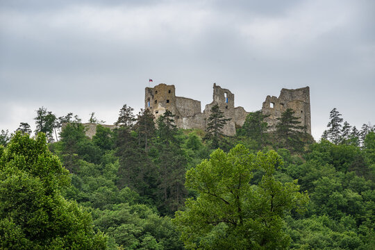 Reviste Castle ruin flying the Slovak flag above forested hills on the Hron river, Revistske Podzamcie, Slovakia