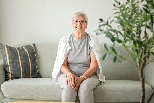 Portrait of elderly woman over grey background sit on sofa
