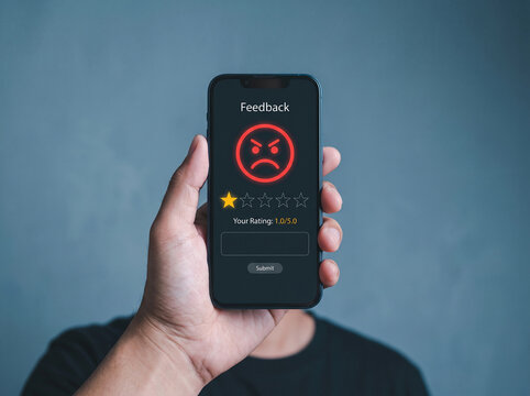 Hand holding smartphone displaying a low rating with a frowny face, representing negative feedback and customer dissatisfaction.