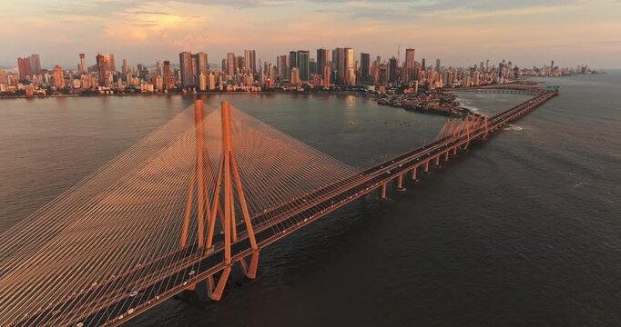 A breathtaking aerial drone view of Mumbai City during the golden evening in the monsoon season, featuring the iconic Bandra-Worli Sea Link stretching across the Arabian Sea.