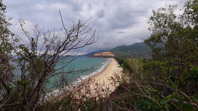 Scenic view of Quy Hoa Beach from Ghenh Rang Park in Quy Nhon, Vietnam, featuring sandy beach, ocean waves, rocky coastline and tropical coastal landscape.