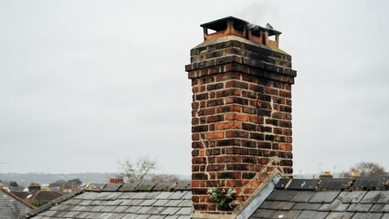Naklejka premium Close-up of Traditional Brick Chimney on Residential Roof in Overcast Weather