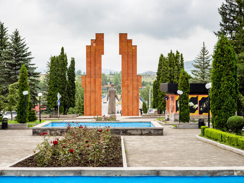 Stepanavan, Armenia - July 18, 2026: flowerbed and view of Stepan Shaumian Monument on central square in Stepanavan city in Lori Province of Armenia on overcast summer day