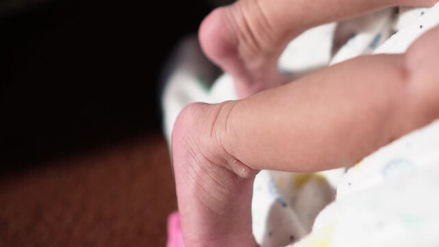 Soft newborn foot and leg details wrapped in patterned blanket. Gentle natural lighting highlights delicate skin texture and tiny toes. Ideal for parenting, infant care, or baby product visuals.
