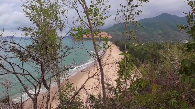 Scenic view of Quy Hoa Beach from Ghenh Rang Park in Quy Nhon, Vietnam, featuring sandy beach, ocean waves, rocky coastline and tropical coastal landscape.