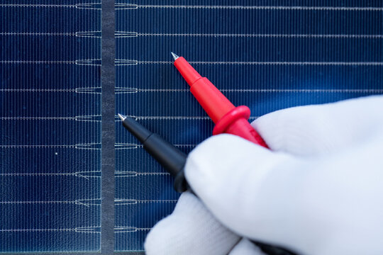 Technician Testing Solar Cells with Electrical Multimeter Probes