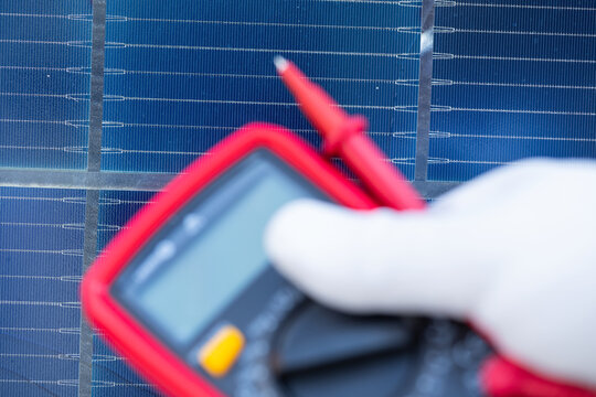 Technician Testing a Solar Panel with a Digital Multimeter