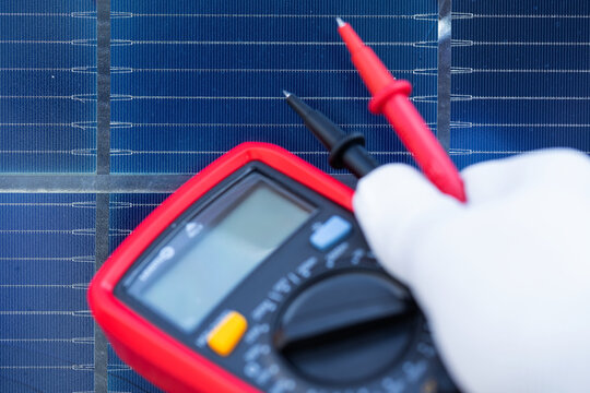 Technician Testing a Solar Panel with a Digital Multimeter