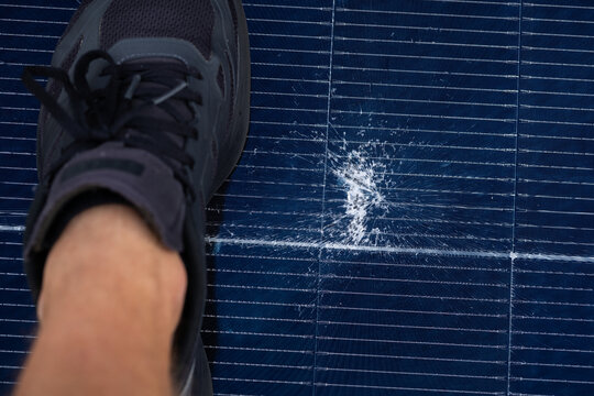 Person Stepping on a Cracked and Damaged Solar Panel