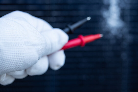 Technician Testing a Cracked Solar Panel with Multimeter Probes