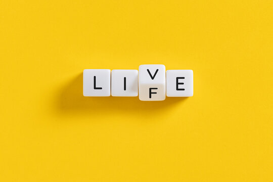 live and life concept spelled on white blocks on yellow background