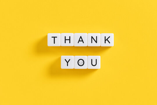 thank you message on white blocks with smiley face on yellow background