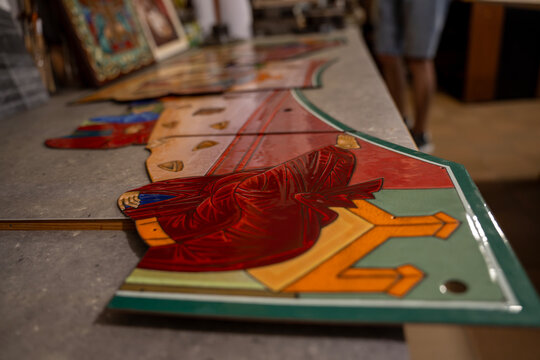 Orthodox painted icon fragments placed on workbench in art restoration workshop, depicting biblical scenes for church iconostasis manufacturing and preservation.