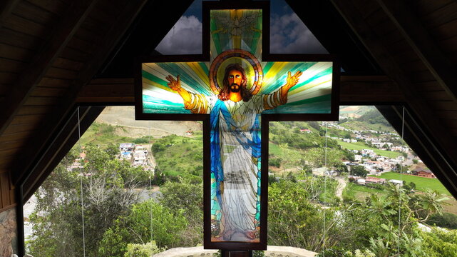 Aerial view of a stained glass cross depicting Jesus in the Portezuelo chapel overlooking the lush green landscape of Constanza, La Vega, Dominican Republic.