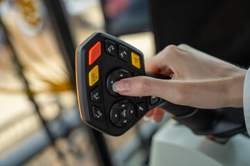 Operator hand controlling multifunctional joystick with buttons inside modern agricultural combine harvester or tractor cabin. © Marina