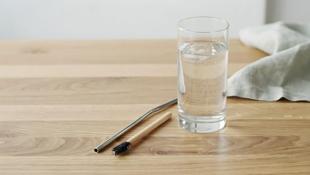 Clear glass filled with drinking water and two chopsticks on a wooden table