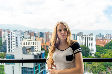 Naklejka premium Blonde woman on balcony with city skyline