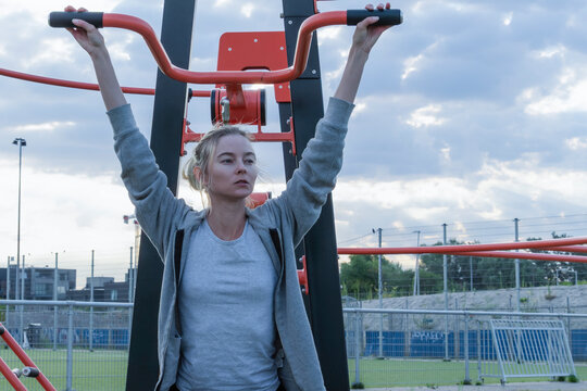 Woman doing lat pulldown exercise on outdoor fitness machine street gym