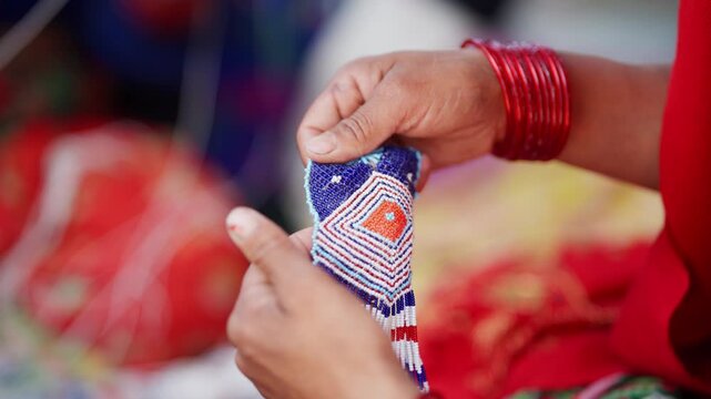 Close up of hands with red bangles gently holding finished blue and white pote glass bead pendant in far west Nepali craft setting