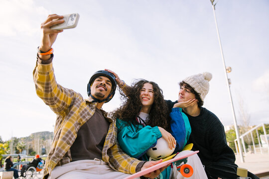 Gen Z friends take selfie with skateboard at skatepark