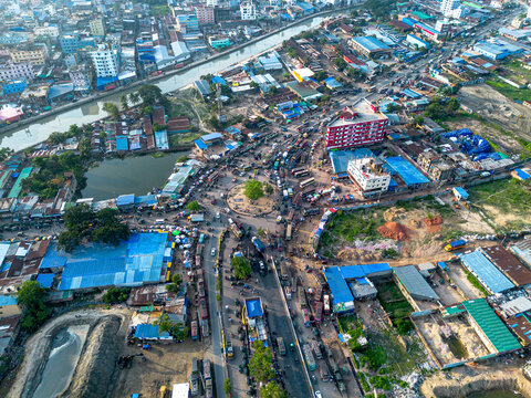 Aerial view of Chottogram Notun Bridge Mor, a busy roundabout intersection featuring dense traffic, urban buildings, and a canal in Chittagong, Chittagong Division, Bangladesh.