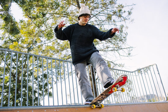 Young skateboarder perform trick at urban skatepark rail