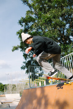 Gen Z skateboarder perform trick at outdoor skatepark ramp
