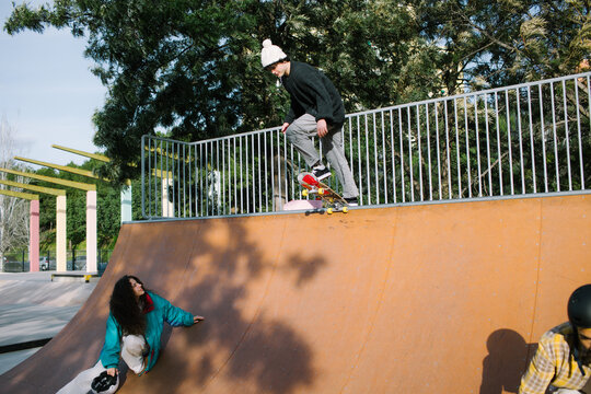 Skateboarder perform trick at outdoor skatepark ramp