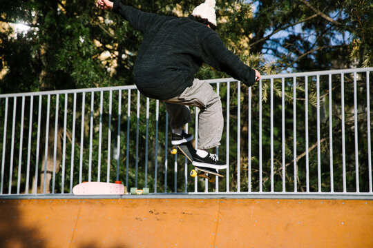 Skateboarder perform aerial trick at outdoor skatepark ramp