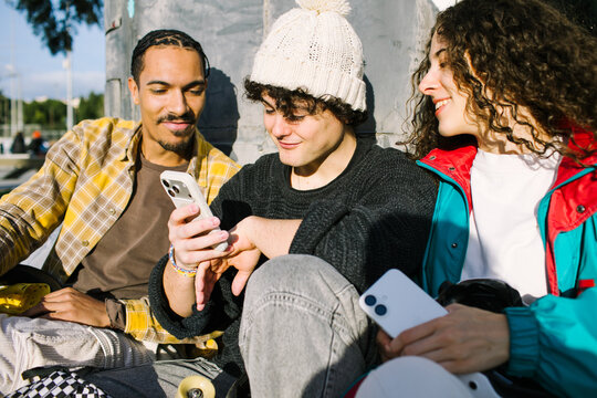 Gen-z friends share smartphone content outdoors in sunlight