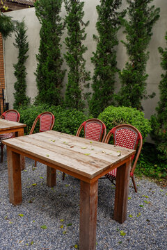 Luxury chair and wooden table set in english garden on a sunny day,outdoor seating for restaurant or cafe,Near paver patio with sitting area and small garden in forest.
