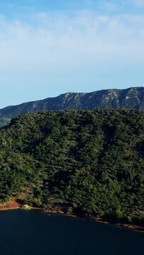Vertical 9:16 aerial video framing showing the right portion of Lac de Salagou in Herault, Occitanie, France. No people or buildings are visible, emphasizing the natural landscape and scenic beauty.