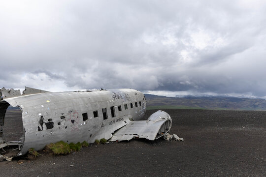 Weathered fuselage of an abandoned airplane wreck on a vast black sand plain under an overcast sky, Solheimasandur, Iceland.