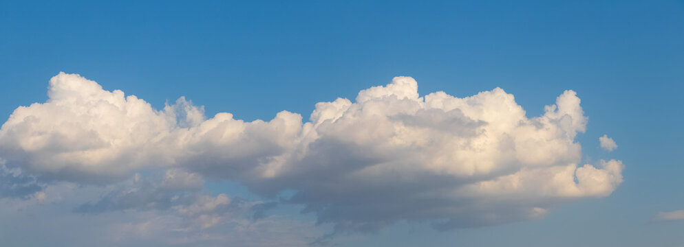 Row of white fluffy clouds against blue sky during day