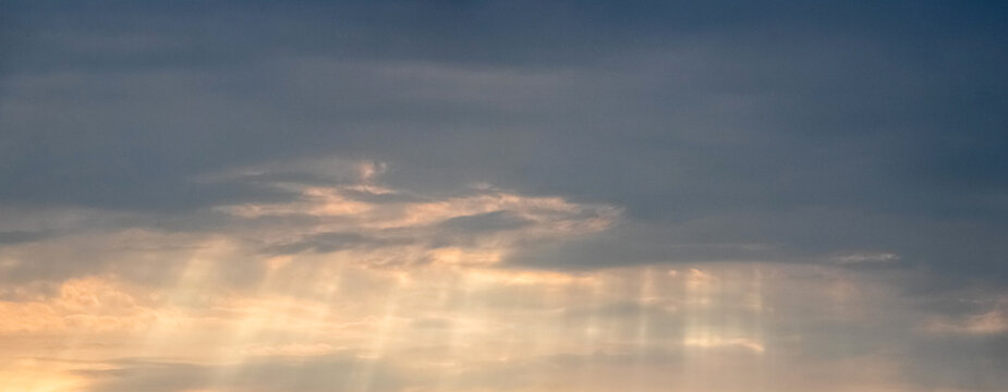 Sun rays breaking through clouds in evening sky