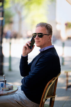 Mature man sitting at a table in a cozy European outdoor cafe
